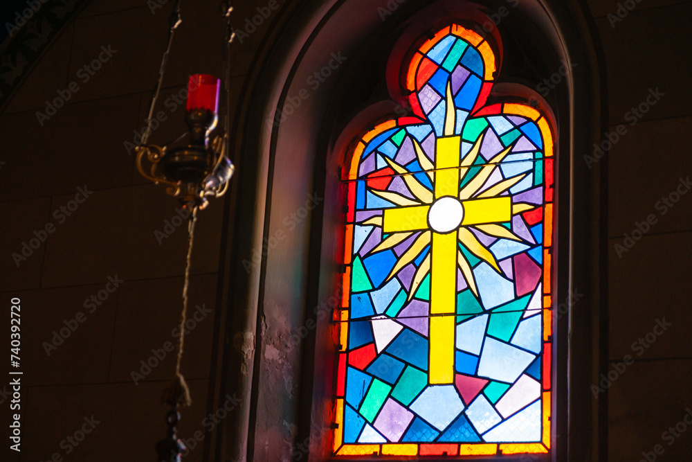 Religious theme yellow cross in leadlight window with colours blue,red and orange.