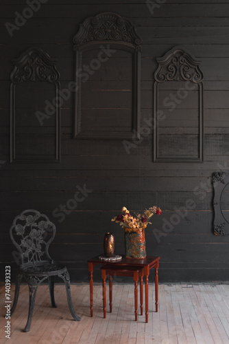 flower on the table and a chair next to it, dark classic interior in wood