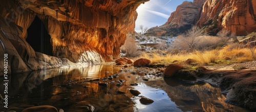A stunning photo capturing the beauty of a red rock canyon with a river flowing peacefully beside a majestic mountain.
