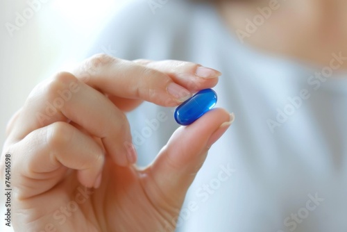 close up image female hand holding a blue pill