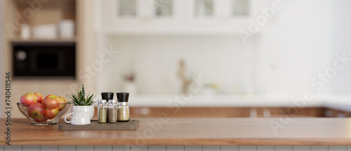 An apple bowl, spice bottles, and a copy space on a wooden kitchen countertop in a modern kitchen.