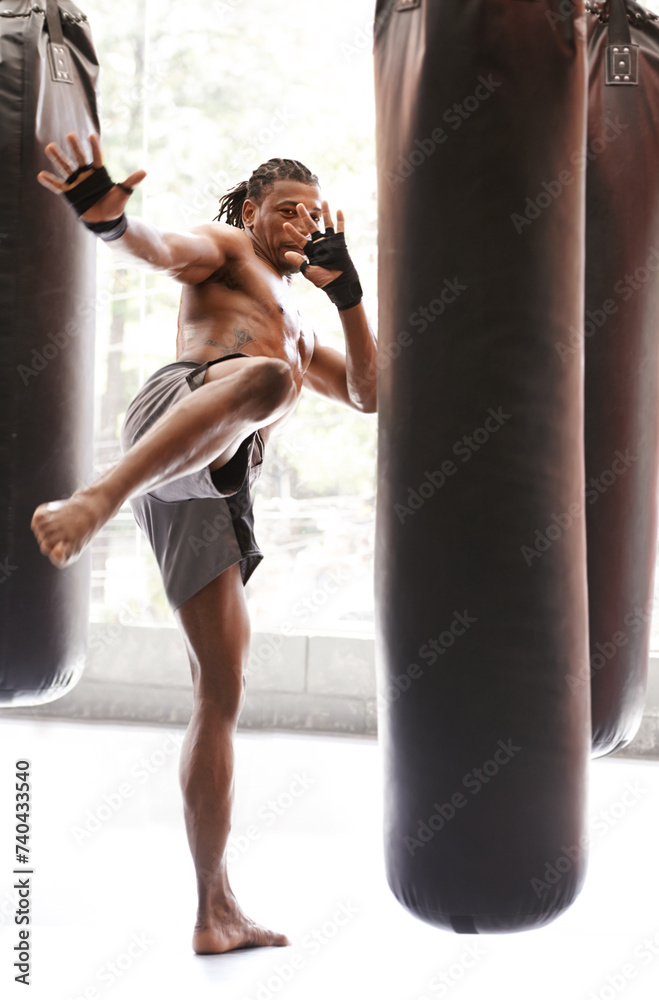 Man, kick boxing and bag with training, foot and combat for exercise with balance, power and precision in gym. African athlete, person or fighter with workout, fitness or strike for challenge in dojo