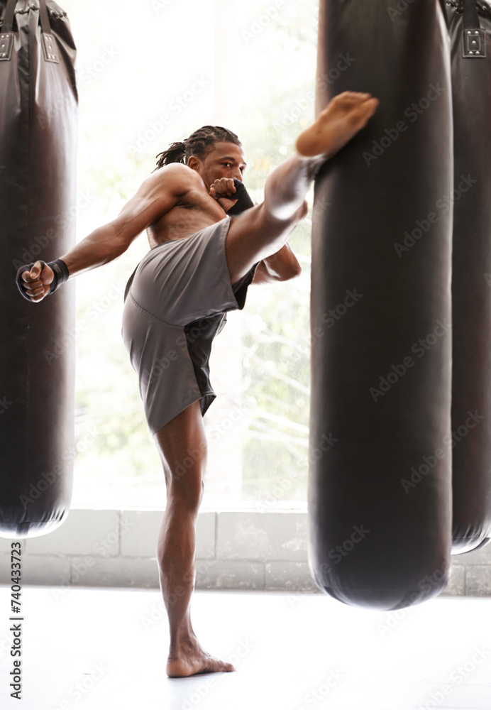 Man, kick boxing and bag with exercise, foot and combat for training with balance, power and precision in gym. African athlete, person or fighter with workout, fitness or strike for challenge in dojo