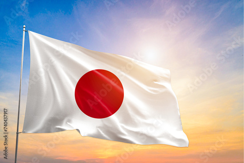 The National flag of Japan blowing in the wind in front of a clear blue sky photo