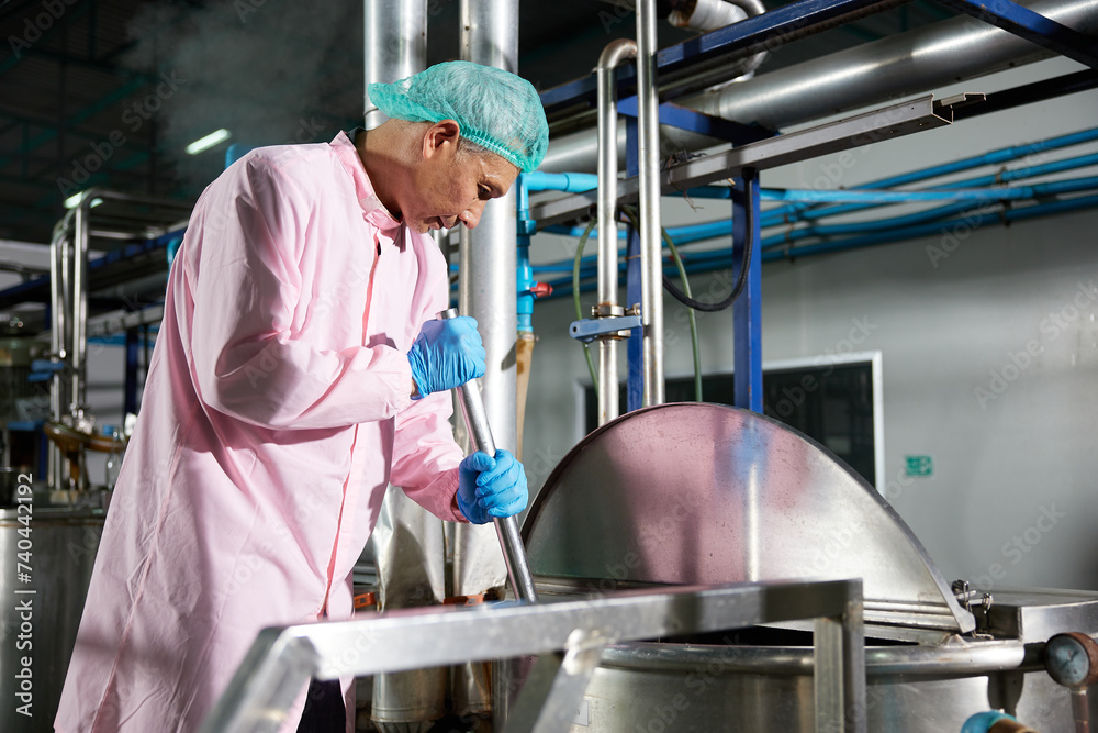 worker stirring water on large industrial pot in the factory worker stirring water on large industrial pot in the factory