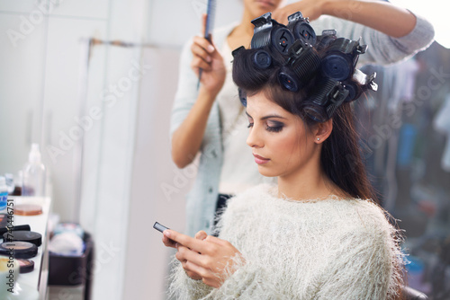 Model, woman and phone with hairdresser for beauty, hair stylist and behind the scenes with social media search. Salon, beautician and person with smartphone for internet scroll while getting ready