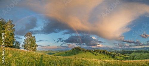 Sunset light and rainbow, rural highlands, panoramic view 