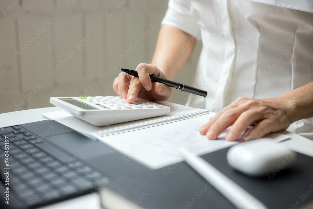 Fototapeta premium Woman using a calculator to calculate a credit card bill information at office