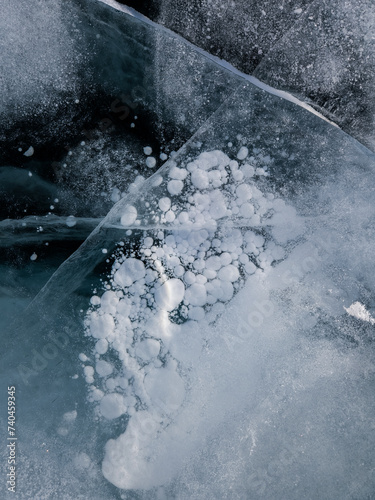 Cracked ice on a frozen lake, top view. the texture of natural blue ice on the surface of a frozen lake on a cold day. Winter seasonal background, layout, flat layer, empty. Selective focus.