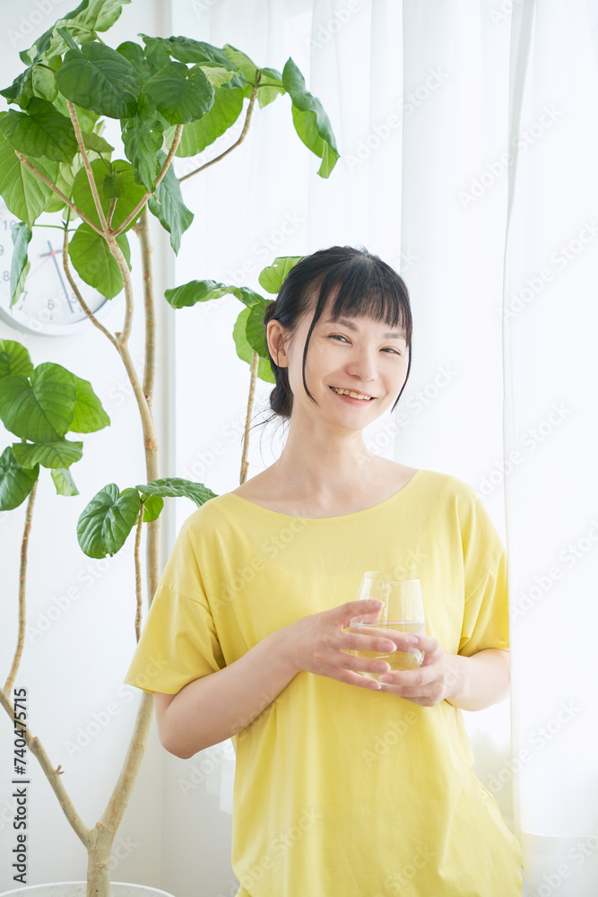 窓辺で水を飲む女性