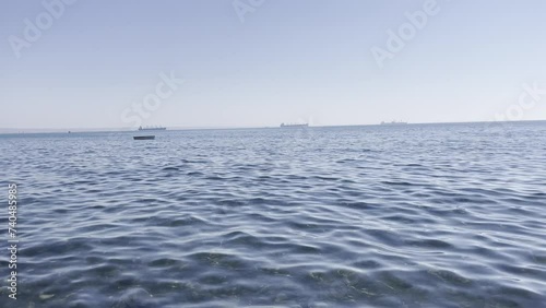 Static shot of calm seas with slight ripples in the water. There are ships in the distance photo
