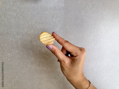 Hand holding Crispy corrugated potato chips or potato chips background. Junk food. Close up photo