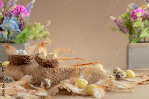 Easter composition with eggs, feathers, and spring flowers on a beige background.