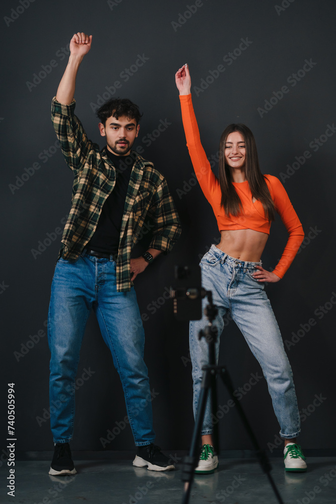Happy caucasian couple recording video for social media or personal family vlog, holding hands up and dancing in front of mobile phone. Video blogging and