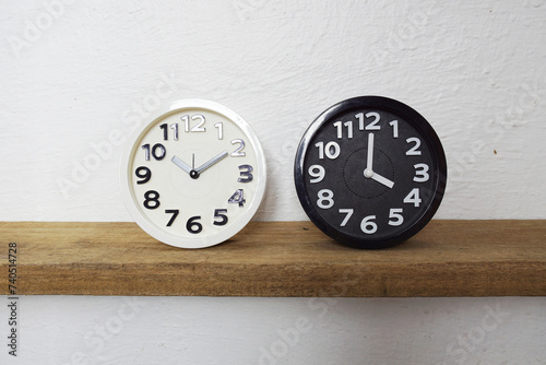 White and Black alram clock show time difference on wooden shelves photo