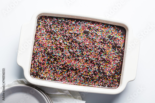 Classic chocolate cake with colored sprinkles in baking dish.