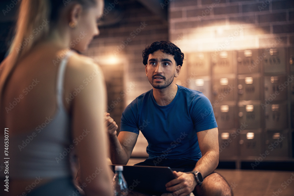 Focused trainer and a young woman doing a health questionnaire in a gym Focused trainer and a young woman doing a health questionnaire in a gym