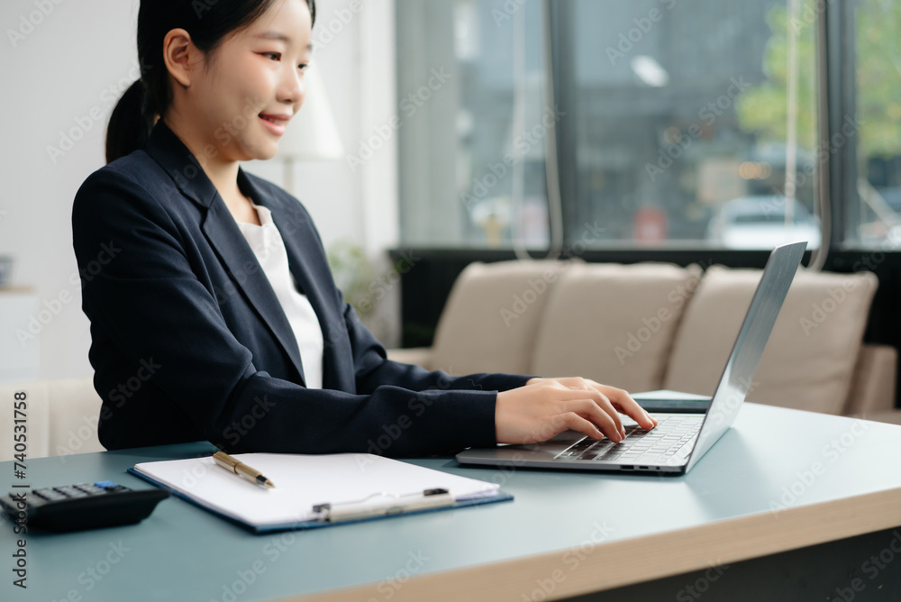 Young beautiful woman typing on tablet and laptop while sitting at the working white table Young beautiful woman typing on tablet and laptop while sitting at the working white table