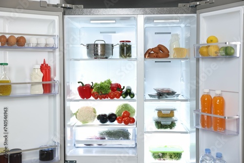 Modern open refrigerator full of different products indoors