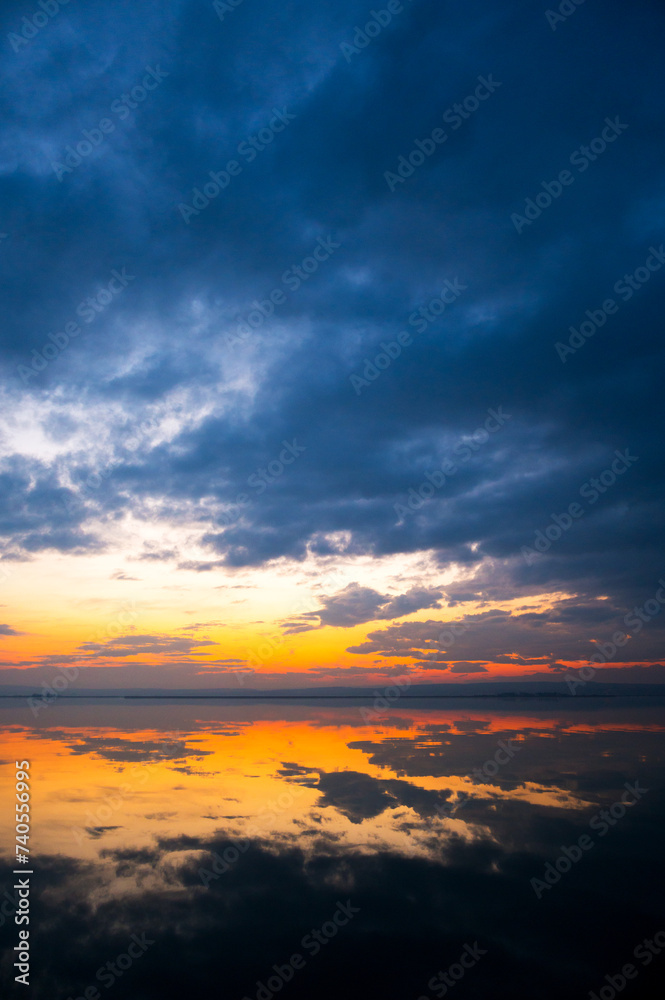 Dramatic sunset at the Lake Neusiedlersee in Austria with colorful orange and red illuminated cloudy sky