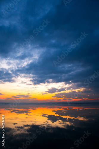 Dramatic sunset at the Lake Neusiedlersee in Austria with colorful orange and red illuminated cloudy sky