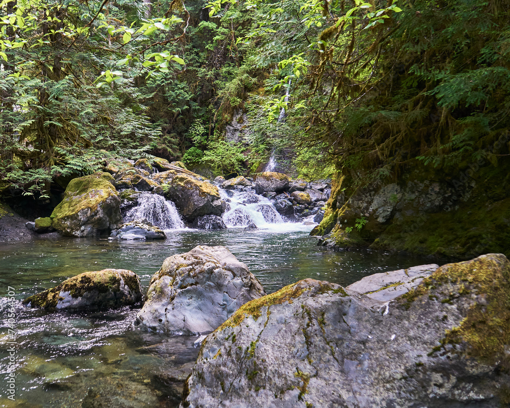 View of the boulders along the river's edge and the waterfall that tumbles through the lush bush. View of the boulders along the river's edge and the waterfall that tumbles through the lush bush.