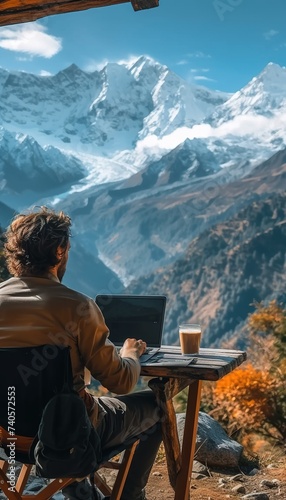 Man working in laptop with a mountain view. Man sitting in the nature and working in laptop.