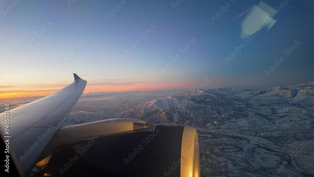 Sunset flight over rugged mountain terrain - view from a commercial jet window at sunset