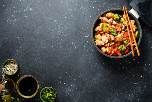 Chicken stir fry with soy sauce and vegetables at black background. Flat lay with copy space.