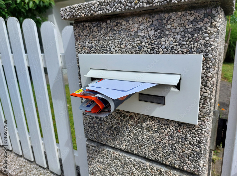 white mailbox with letters and advertise on fence