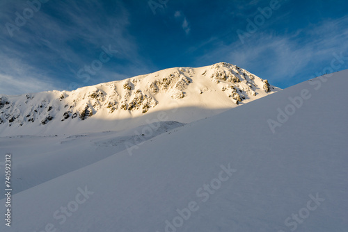 The slope of the ridge illuminated by the first rays of the rising sun. Winter scenery in the morning. © gubernat