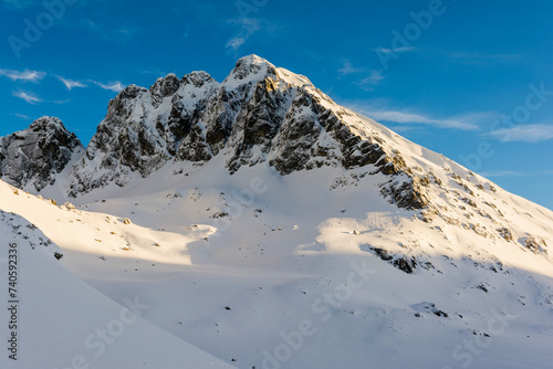 The peak (Kozi vrch, Kozi Wierch) illuminated by the rays of the setting sun in winter in the Polish Tatra Mountains.