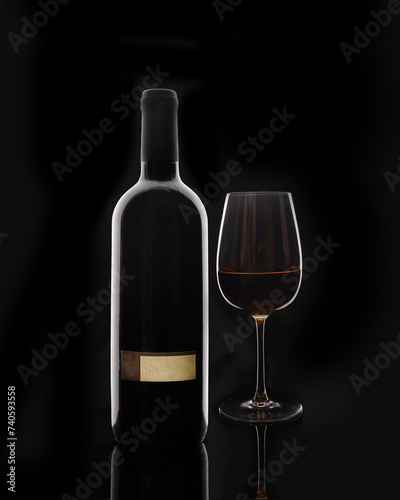 Isolated bottle of red wine and red glass of wine on black background with blank label