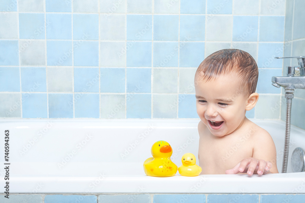 smiling toddler looking at his two rubber duckies in the bathtub smiling toddler looking at his two rubber duckies in the bathtub