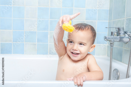 Fotografie Little boy in the bathtub showing his rubber ducky to the camera