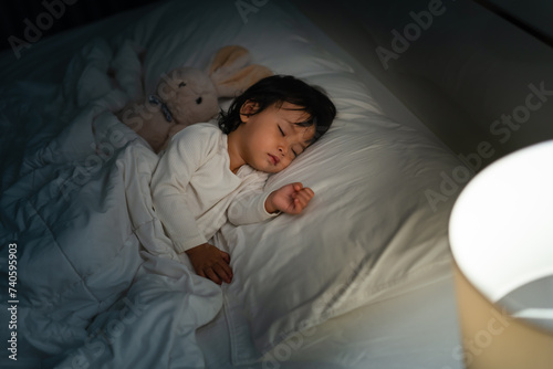 Foto toddler baby sleeping with teddy bear on bed at night