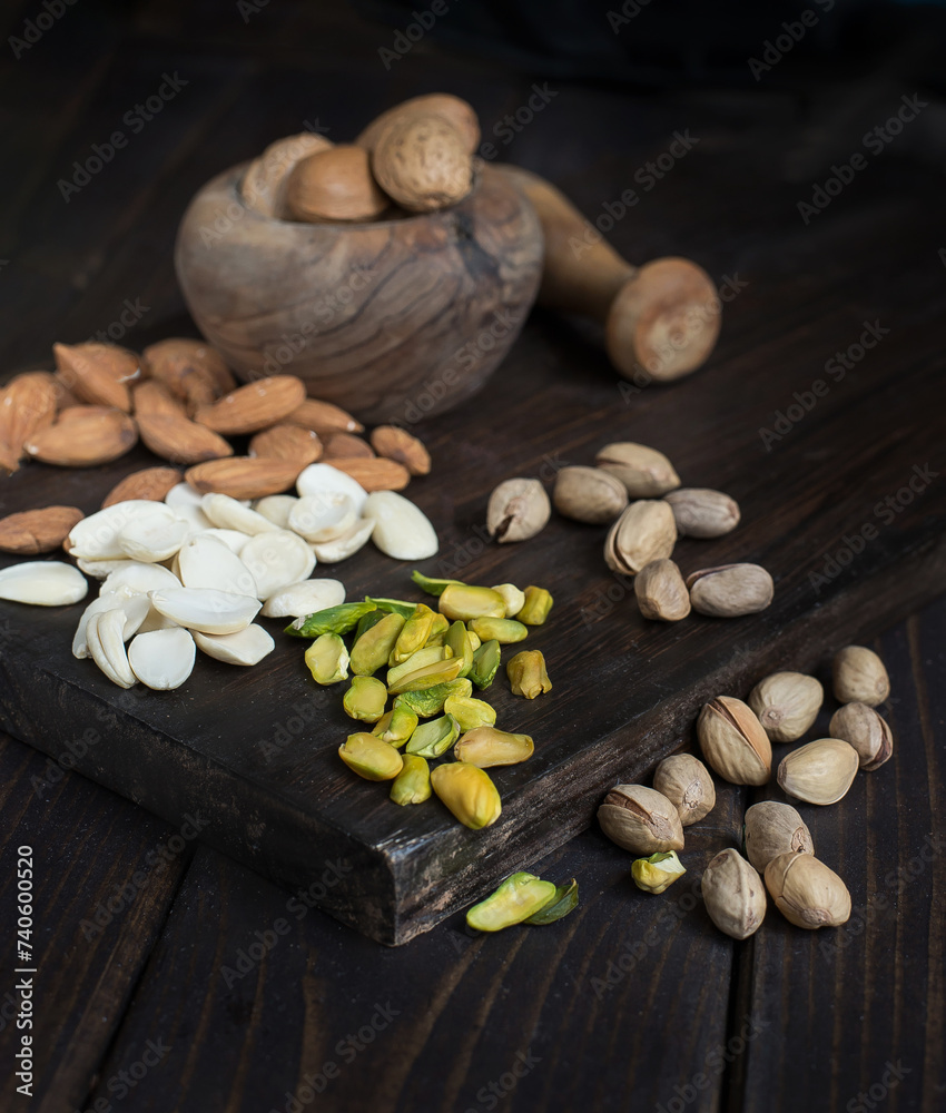 Pistachios, cashews and other nuts on a dark wooden table.