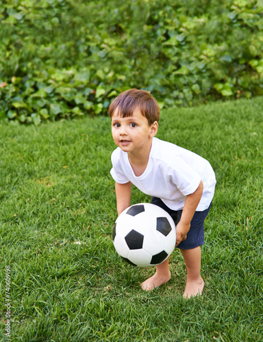 Portrait, boy or catch with soccer ball in park for fun, health or childhood development in Portugal. Happy, confident and male child with football for game or exercise in backyard or garden © Katie/peopleimages.com