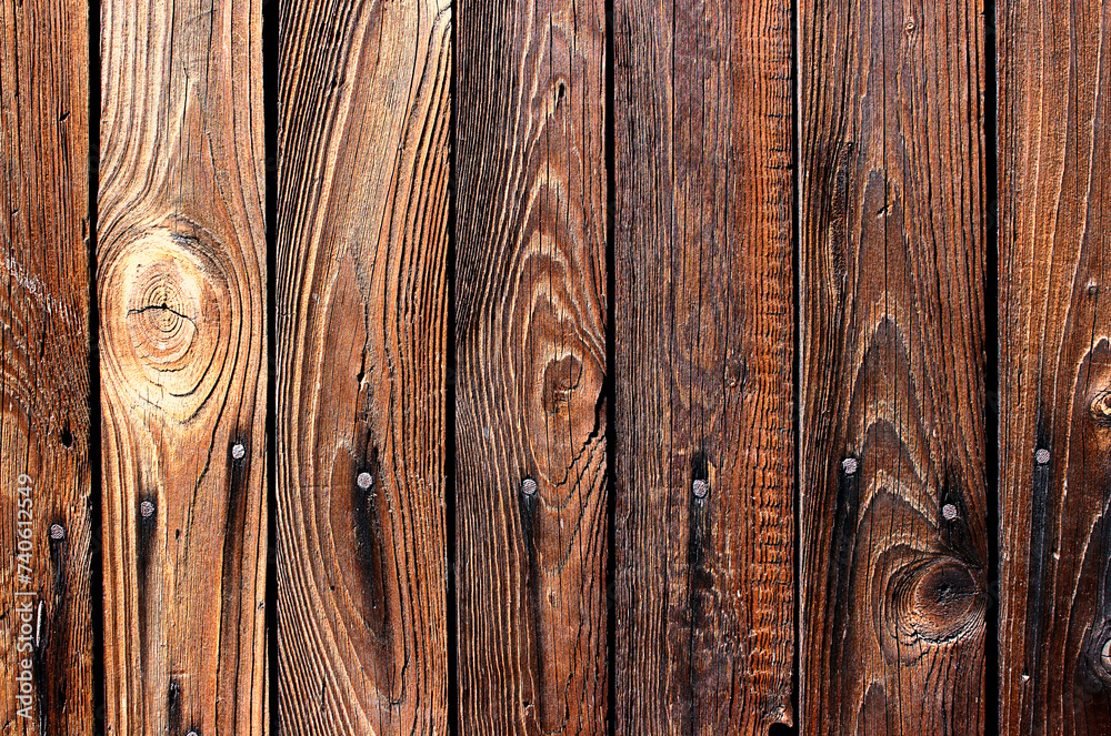 Fototapeta premium Stare deski drewniane w brązowym kolorze przybite gwoździami z widocznymi sękami i słojami ułożone pionowo - tło, tapeta, tekstura
