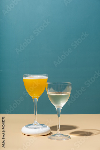 Two glasses with an alcoholic cocktail on a colored background