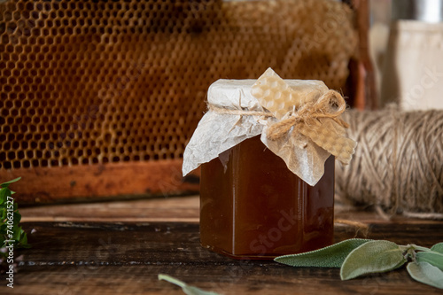 A small jar of honey is decorated with natural fabric