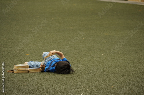 A boy lies on the lawn and read comic books at Kyoto International Manga Museum, Japan.