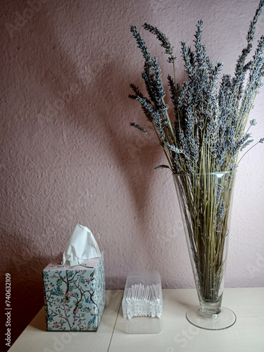 a bouquet of lavender in a glass vase on a table against a pink wall background