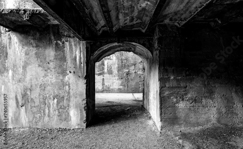 Eerie underpass with shabby concrete walls on an abandoned factory site of a former steelworks in Duisburg in the Ruhr Basin, Germany. Contrasting black and white greyscale in lost place location