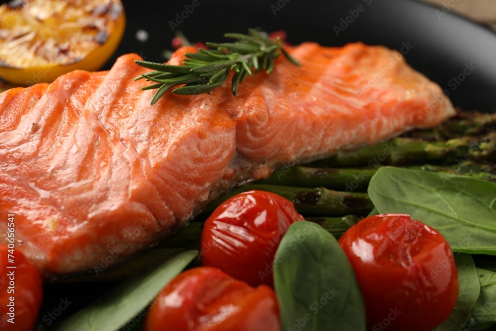 Tasty grilled salmon with tomatoes, spinach and rosemary on plate, closeup Tasty grilled salmon with tomatoes, spinach and rosemary on plate, closeup