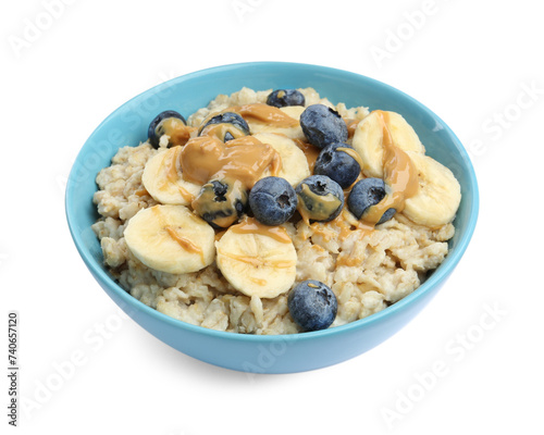 Tasty oatmeal with banana, blueberries and peanut butter in bowl isolated on white