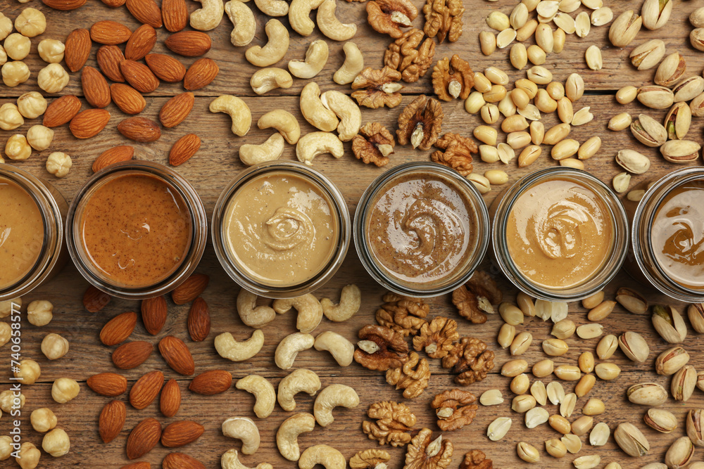Nut butters in bowls and ingredients on wooden table, flat lay Nut butters in bowls and ingredients on wooden table, flat lay
