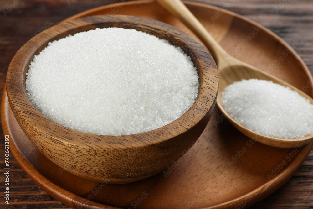 Granulated sugar in bowl and spoon on wooden table, closeup Granulated sugar in bowl and spoon on wooden table, closeup