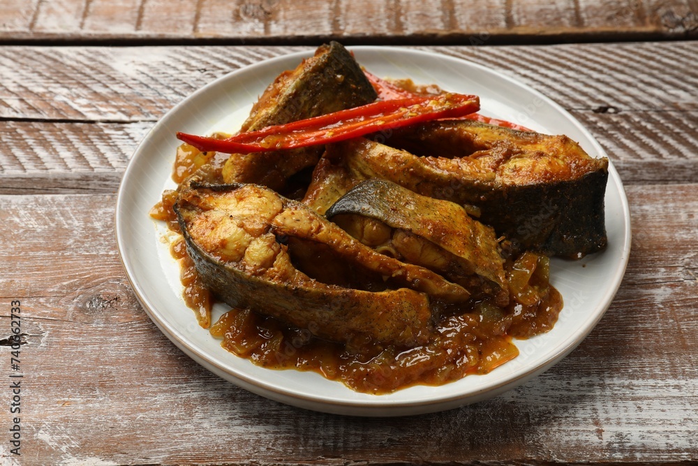 Tasty Indian fish curry on wooden table, closeup Tasty Indian fish curry on wooden table, closeup