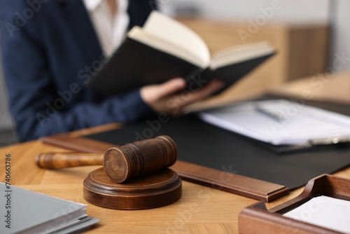 Notary reading book at wooden table in office, focus on gavel